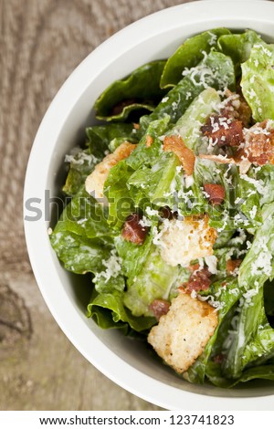 Closed Up Cropped Bowl Of Caesar Salad Placed On Top Of A Wooden Table