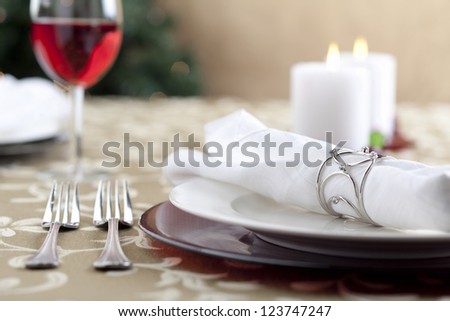 A close-up cropped image of dinnerware set with a blurred candle light background