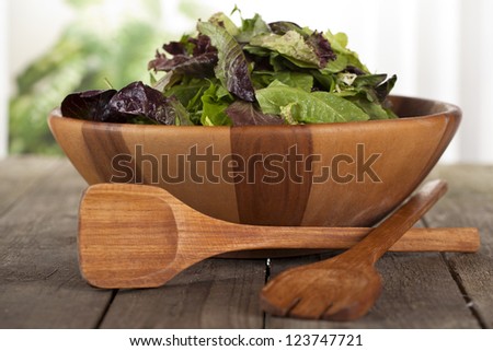 Image of bowl of vegetable salad with wooden utensils