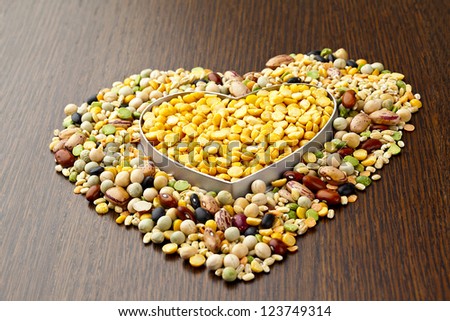 Close-up shot of food grains assorted in heart shape on wooden table.