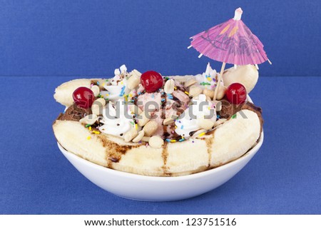 Close-up image of plate with banana split sundae and cherry toppings isolated over the blue background