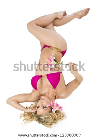 Sexy young woman wearing pink bikini and holding flower lying on back on white background