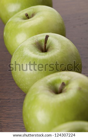 Row of Granny Smith apple set on a wooden table.