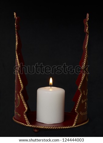Close-up image of a red vintage candle holder with lighted candle on a dark background