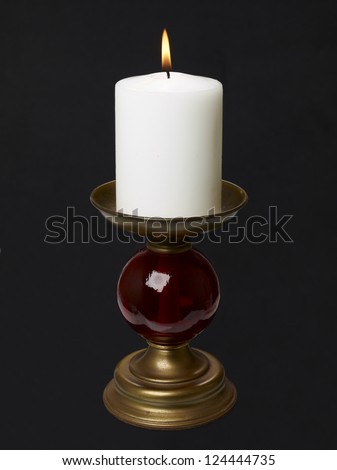 Retro style candle holder with lighted candle over a black background