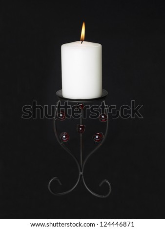 Image of lighten candle in black candle holder against black background