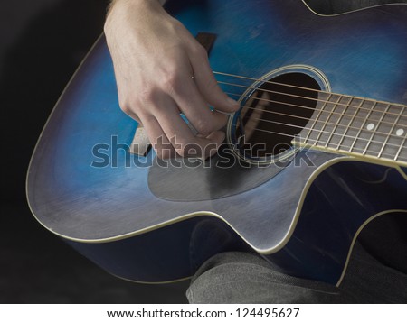 Close-up image of a male performer playing the blue guitar
