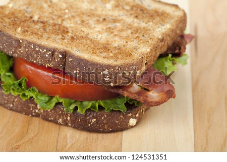 Cropped image of bacon sandwich against wooden background