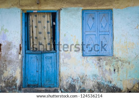 A blue door with a curtain and a closed window in Kochi, India.