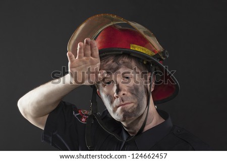 Exhausted Fireman wiping his dirty forehead using his hand