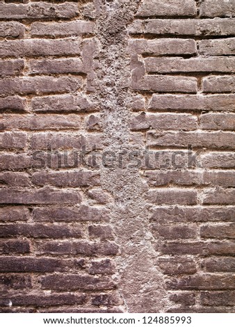 A brick wall that has a large crack that was repaired with plaster