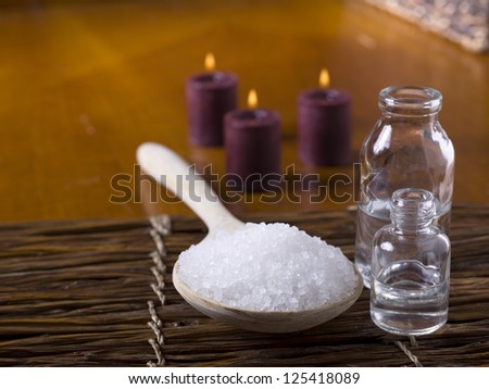 Close-up image of plastic spoon with spa salt and blurred lighted candle