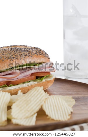 Closed up chips, ham sandwich, and glass of soda