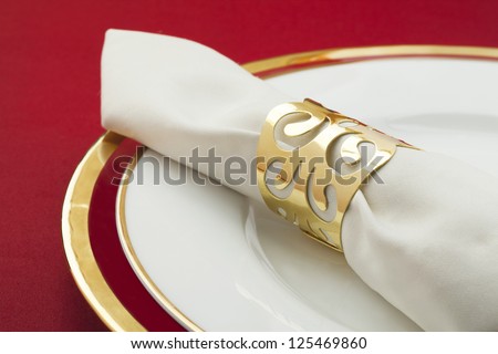 Cropped image of a white ring napkin on a round plate isolated on a red background