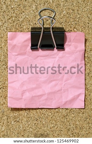 Wrinkled pink memo note with black binder clip