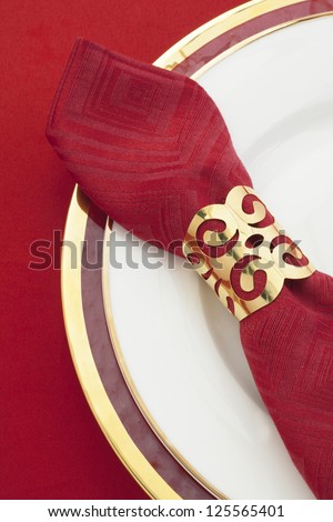 Red satin napkin with golden ring on a white plate