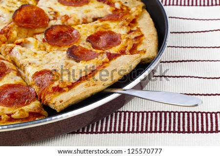 A cropped image of a hot baked pan pizza on a place mat