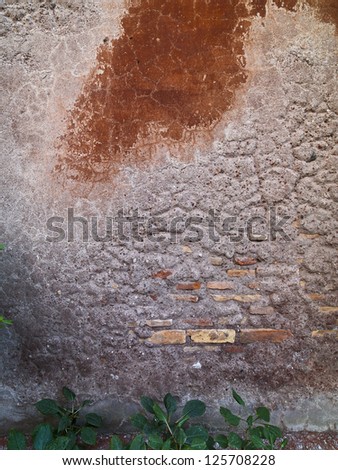 A wall that has been worn down to reveal bricks and cement