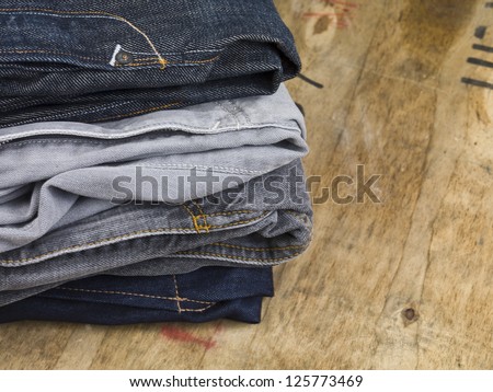 Close up image of stack of folded men\'s jeans on wooden table