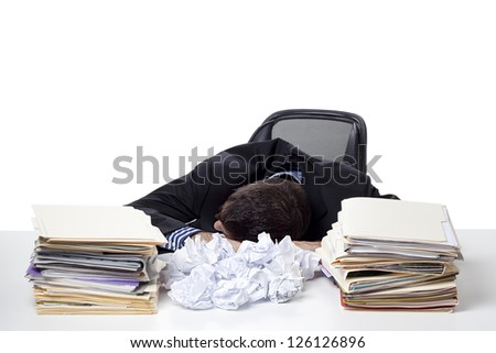 Exhausted businessman sleeping at work with files and paper balls on his desk