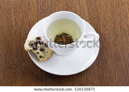 Close-up shot of lime tea with missing bite of chocolate chip cookies on wooden table.