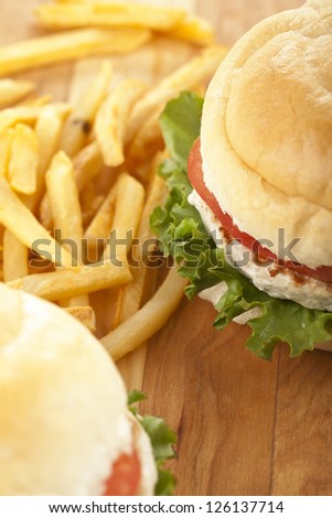 Close-up image of chicken hamburgers and potato fries on a wooden table