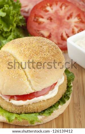 Close-up image of delicious crispy chicken burger with ingredients on the background