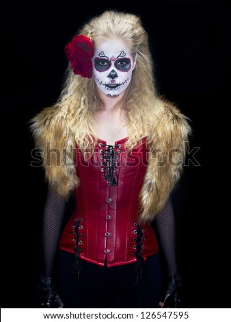 Portrait shot of a scary girl wearing traditional sugar skull make-up against black background.