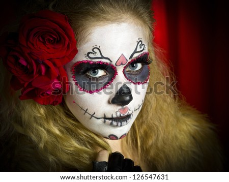 Portrait shot of a scary woman wearing sugar skull and roses in hair.