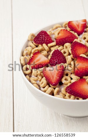 Close up image of bowl of cereal with strawberries in wooden table