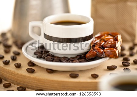 Black coffee and almond bar with coffee beans on a white saucer