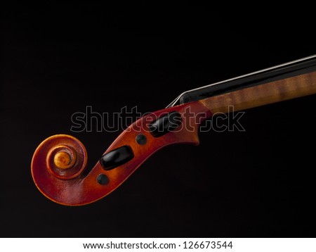 Close up image of violin peg box against dark background