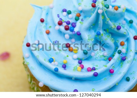 Close-up cropped image of a cupcake with blue cream and sugar icing.