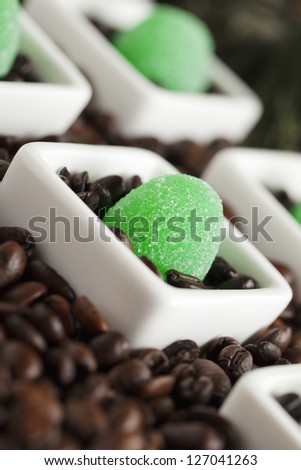 Green jelly candies and coffee beans on a dish