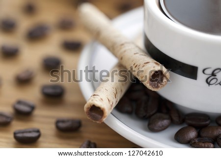 Close-up shot of cup and saucer, coffee beans with cookie sticks