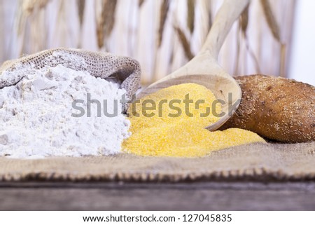 Image of bread ingredients with maize flour and a sack of wheat flour on table