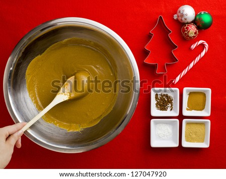 Close-up top view of a person holding spatula in chocolate syrup with cake ingredient over red background.