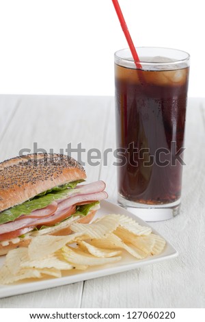 Yummy snack consisting of cola, ham sandwich and chips
