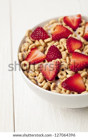 Rice Cereal Rings with milk and fresh strawberries on a white bowl