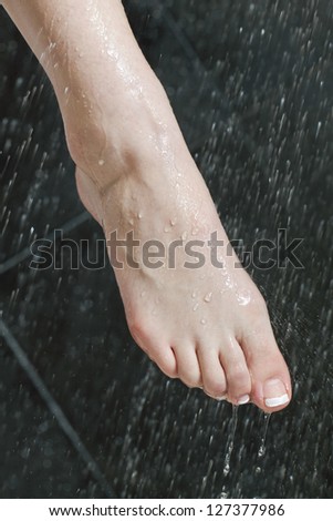 Close-up image of a woman\'s wet foot on shower