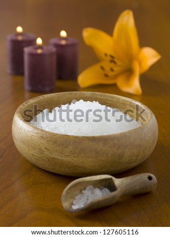 Bowl of spa salt with lighted candles and lily flower