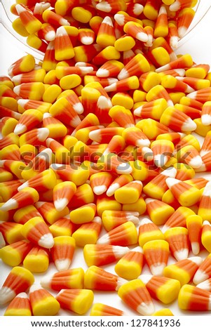 Candy corn spilled from a plastic container.