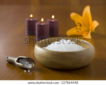 Close-up image of a spa salt with flower and lighted candles on the wooden table
