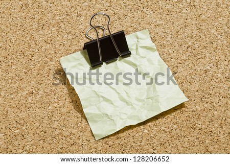 Close up image of crumpled green adhesive paper with black paper clip
