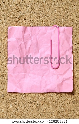 Close-up image of a crumpled paper with pink paper clip