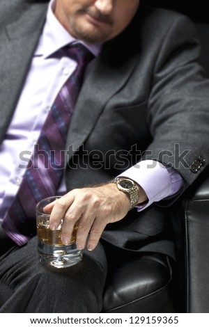 Closeup cropped shot of a gangster in full suit holding whiskey glass in hand