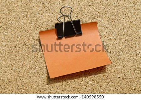 Image of orange adhesive paper with black paper clip