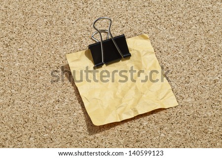 Crumpled yellow memo note with binder clip