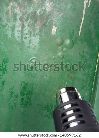 Cropped image of heat gun over the green chair background