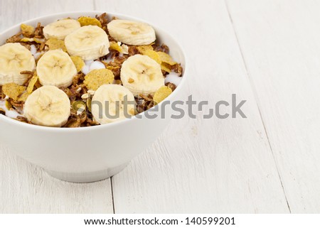 Cropped image of a bowl with cereals and a slice banana isolated on a white background